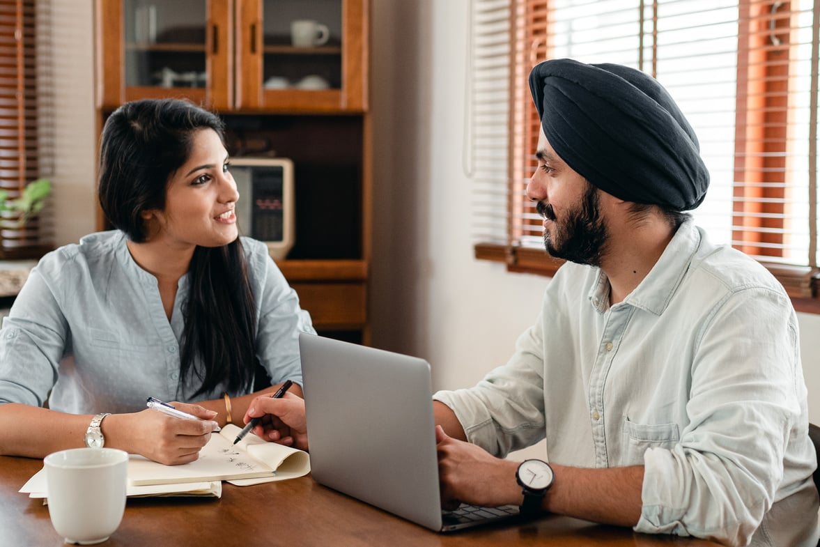 Happy Indian partners talking while working on project using laptop